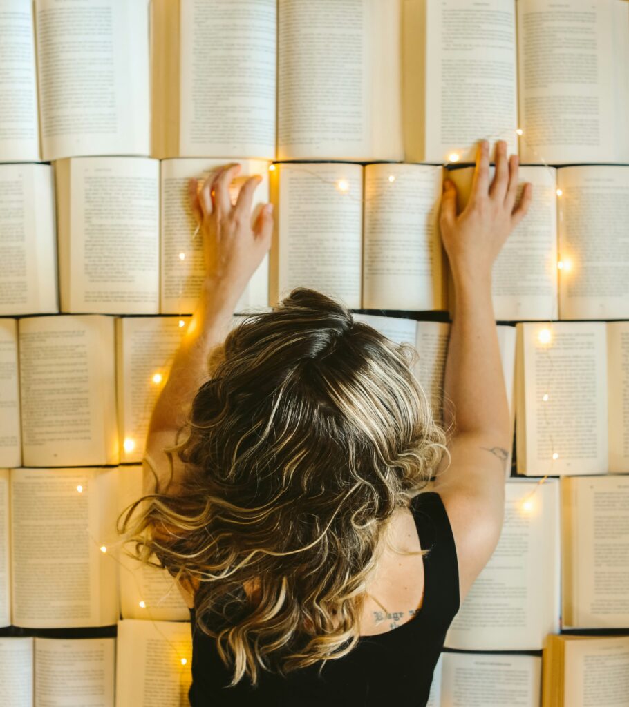 a woman with glowing hands crawls on top of a collection of open books