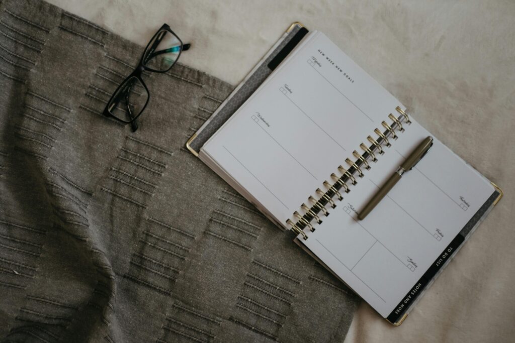 A schedule notebook sitting next to a pair of glasses.