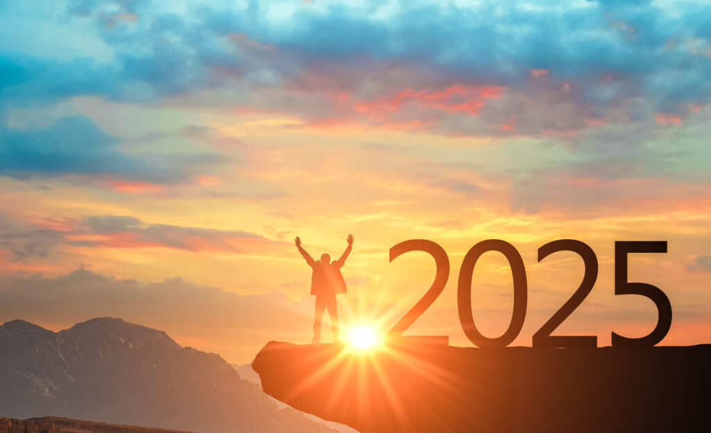 a man celebrating on a cliff face in front of a sunset and the year 2025 sitting beside him.